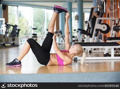 Cute young woman stretching and warming up for her training at a gym