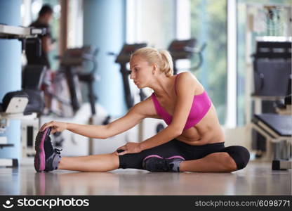 Cute young woman stretching and warming up for her training at a gym