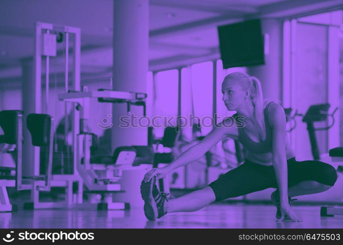 Cute young woman stretching and warming up for her training at a gym duo tone. woman stretching and warming up for her training at a gym