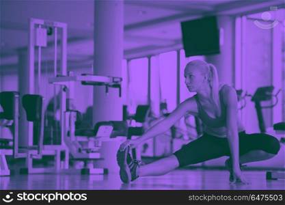 Cute young woman stretching and warming up for her training at a gym duo tone. woman stretching and warming up for her training at a gym