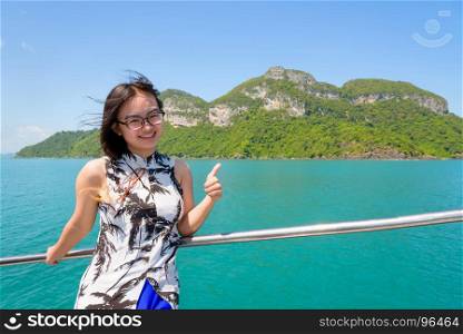 Cute young woman thumb up. Cute young woman with eyeglasses thumb up the beautiful natural of the sea island and sky in summer on the boat while cruising at Mu Ko Ang Thong National Park, Surat Thani, Thailand