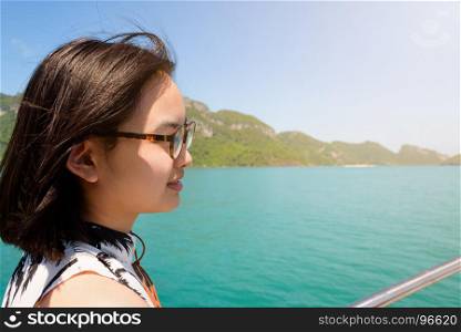 Cute young woman under sunlight. Cute young woman with eyeglasses smiling happily on the boat while cruising the natural of the sea island and under sunlight summer at Mu Ko Ang Thong National Park, Surat Thani, Thailand