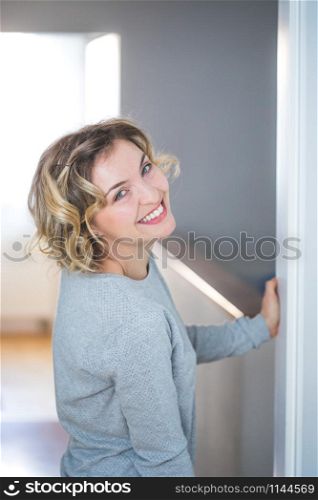 Cute young woman with blonde curly hair is happy about her new home