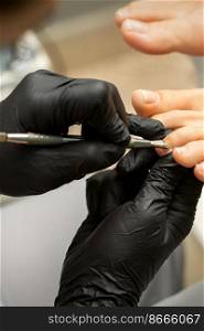 Cuticle Removal on Toes. Hands in black gloves of pedicure master remove cuticle on female toes by pusher. Cuticle Removal on Toes. Hands in black gloves of pedicure master remove cuticle on female toes by pusher.