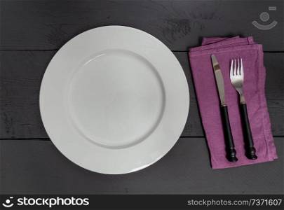 Cutlery and plate on black wooden background.. Cutlery and plate on black wooden background