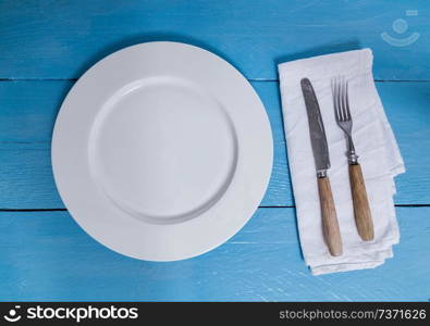 Cutlery and plate on blue wooden background.. Cutlery and plate on blue wooden background