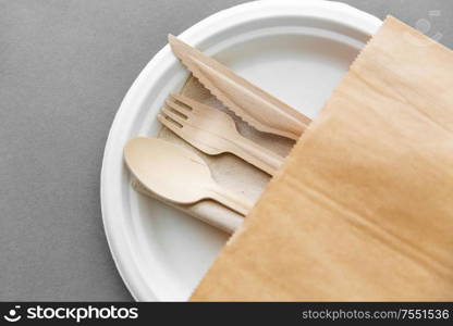 cutlery, recycling and eco friendly concept - set of wooden spoon, fork and knife on paper plate on grey background. wooden spoon, fork and knife on paper plate