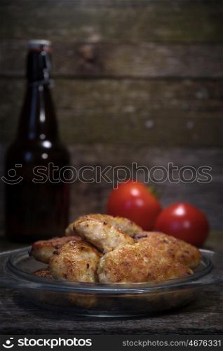 Cutlet and tomato lie on the background of wood. Cutlet and tomato