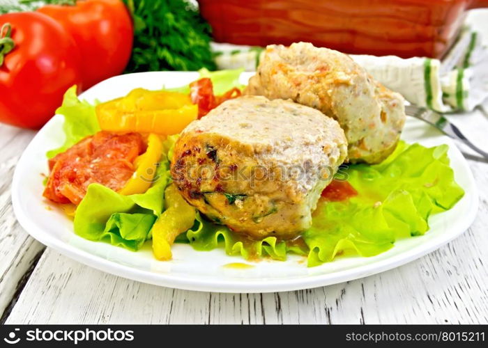 Cutlet of turkey meat with lettuce, tomato and pepper in a bowl, parsley, a towel and a fork on the background of wooden boards