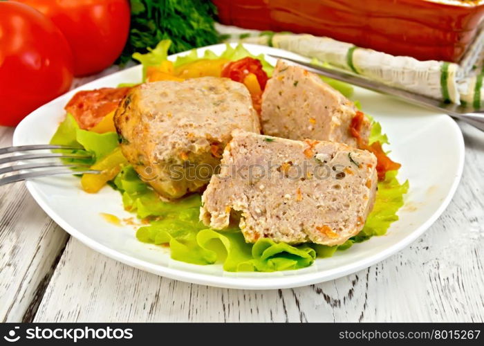 Cutlet of turkey meat with lettuce, tomato and yellow pepper in a dish, parsley, a towel and a fork on the background of wooden boards