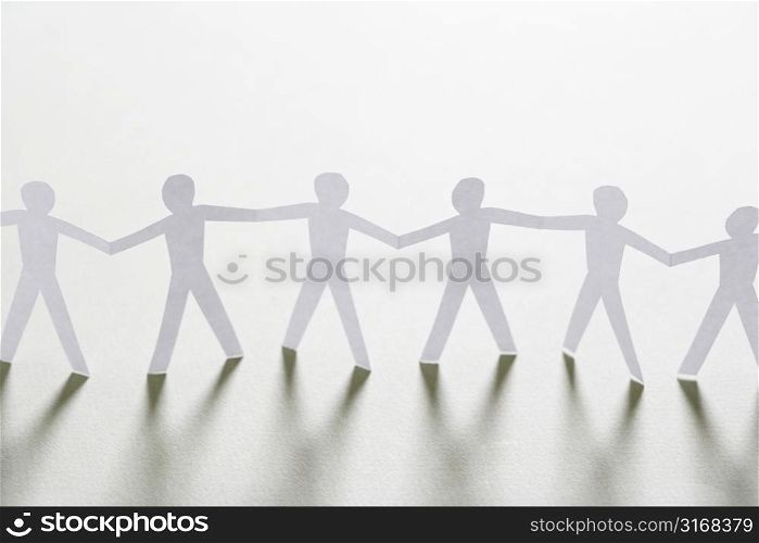 Cutout paper men standing holding hands.