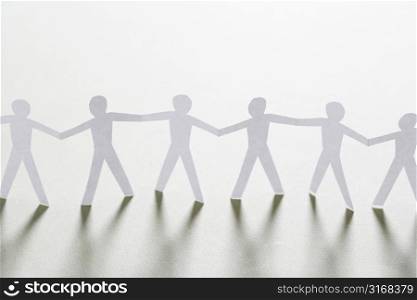 Cutout paper men standing holding hands.