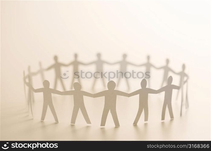 Cutout paper people standing in circle holding hands.