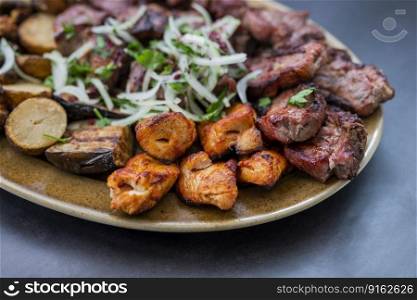 cuts of meat barbecue grilled pork and beef and chicken on a plate with onions in a restaurant