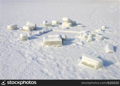 Cutted out pieces of ice on the surface of a frozen lake near the hole