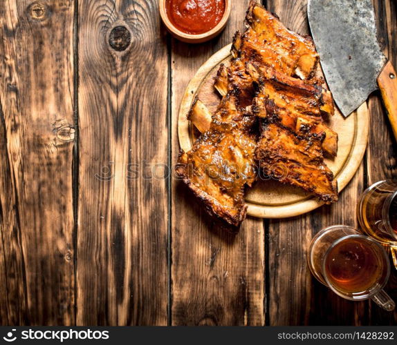 Cutting ax to the ribs of the grill with a beer. On a wooden table.. Cutting ax to the ribs