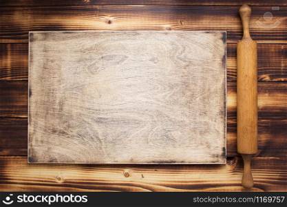 cutting board and rolling pin at rustic wooden plank background, top view