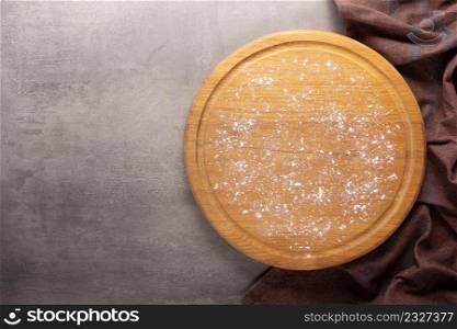Cutting board and scattered flour powder at stone background top table. Wooden pizza board