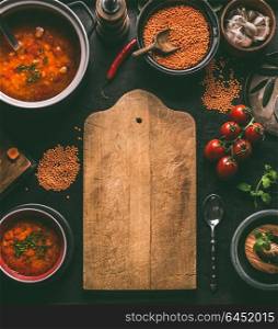 Cutting board food background of healthy vegan lentil dishes on dark kitchen table background with ingredients, top view. Vegetarian food. Clean diet eating. Source of plant based protein. Copy space