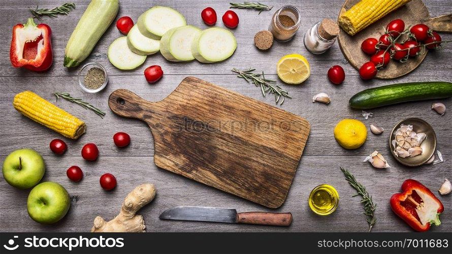 cutting board, lay around the cucumbers, peppers, tomatoes on a branch, lemon, corn, zucchini, apples, butter, spices and herbs, Healthy foods, cooking and vegetarian concept. place for text,frame