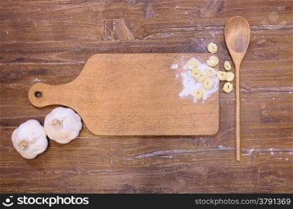 Cutting board wooden with tortellini on kitchen table.