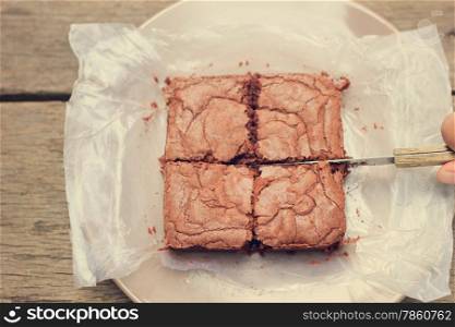 Cutting crispy homemade brownie with retro filter effect