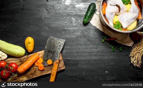 Cutting vegetables with an ax to chicken soup. On a black wooden background.. Cutting vegetables with an ax to chicken soup.