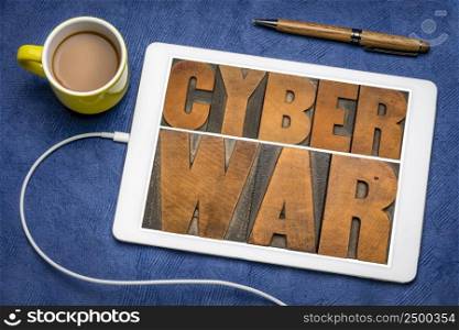 cyber war - words in vintage letterpress wood type on a digital tablet, cyberwarfare and digital attacks concept