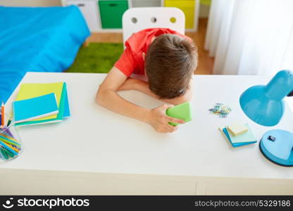 cyberbullying, technology and people concept - tired or sad student boy with smartphone lying on desk at home suffering from bullying. tired or sad student boy with smartphone at home