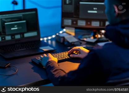 cybercrime, hacking and technology concept - close up of male hacker in dark room writing code or using computer virus program for cyber attack. hacker using computer virus for cyber attack