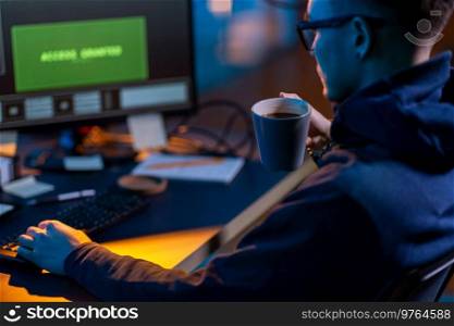 cybercrime, hacking and technology concept - close up of male hacker in dark room drinking coffee and using computer virus program for cyber attack. hacker using computer virus for cyber attack