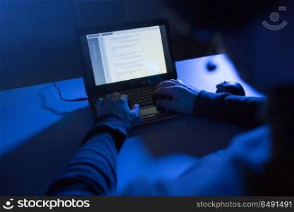 cybercrime, hacking and technology concept - hands of hacker in dark room writing code or using laptop computer virus program for cyber attack. hacker using laptop for cyber attack. hacker using laptop for cyber attack
