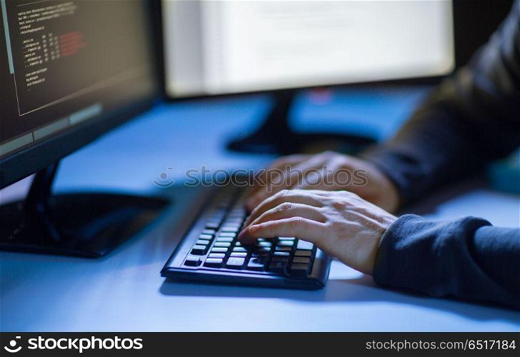 cybercrime, hacking and technology concept - hands of hacker in dark room writing code or using computer virus program for cyber attack. hacker using computer virus for cyber attack. hacker using computer virus for cyber attack