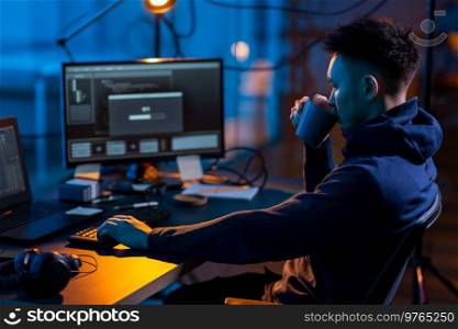 cybercrime, hacking and technology concept - male hacker in dark room drinking coffee and using computer virus program for cyber attack. hacker using computer virus for cyber attack