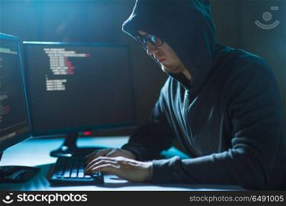 cybercrime, hacking and technology concept - male hacker in dark room writing code or using computer virus program for cyber attack. hacker using computer virus for cyber attack. hacker using computer virus for cyber attack
