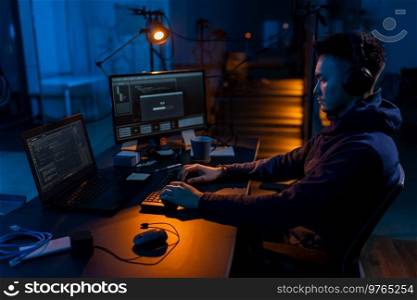 cybercrime, hacking and technology concept - male hacker in dark room writing code or using computer virus program for cyber attack. hacker using computer virus for cyber attack
