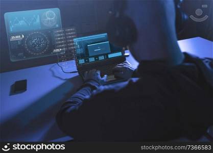 cybercrime, hacking and technology concept - male hacker in headphones with progress loading bar on laptop computer screen wiretapping or using virus program for cyber attack in dark room. hacker with progress bar on laptop in dark room