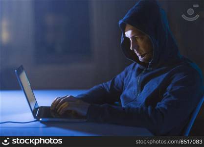 cybercrime, hacking and technology concept - male hacker with microphone using laptop computer for cyber attack or wiretapping in dark room. hacker with microphone and laptop in dark room. hacker with microphone and laptop in dark room