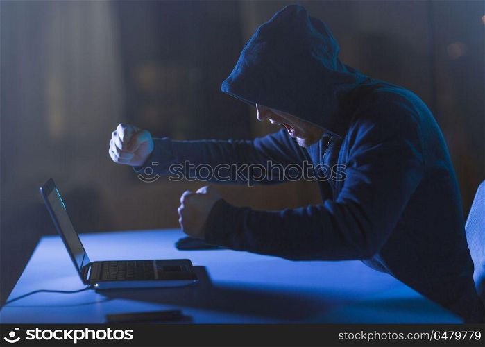 cybercrime, hacking and technology crime - angry male hacker with laptop computer shouting in dark room. angry hacker with laptop shouting in dark room. angry hacker with laptop shouting in dark room