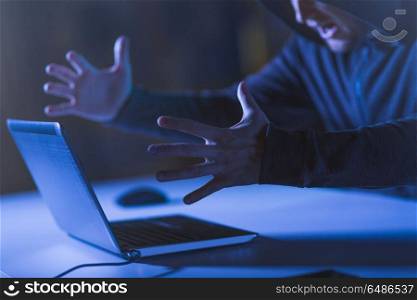 cybercrime, hacking and technology crime - angry male hacker with laptop computer shouting in dark room. angry hacker with laptop shouting in dark room. angry hacker with laptop shouting in dark room