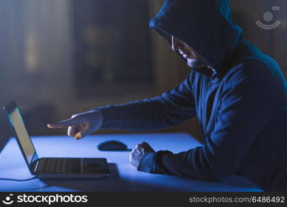 cybercrime, hacking and technology crime - male hacker pointing finger at laptop computer in dark room. hacker pointing at laptop computer in dark room. hacker pointing at laptop computer in dark room