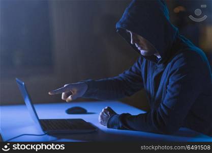 cybercrime, hacking and technology crime - male hacker pointing finger at laptop computer in dark room. hacker pointing at laptop computer in dark room. hacker pointing at laptop computer in dark room