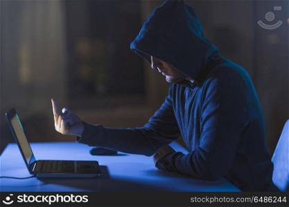 cybercrime, hacking and technology crime - male hacker showing middle finger to laptop computer in dark room. hacker showing middle finger to laptop. hacker showing middle finger to laptop