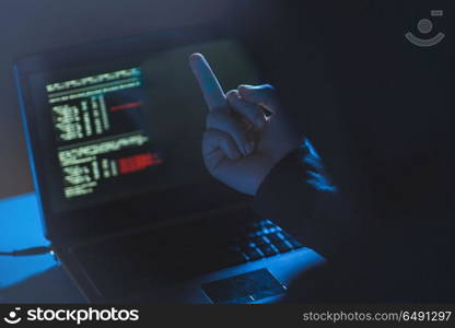 cybercrime, hacking and technology crime - male hacker showing middle finger to laptop computer in dark room. hacker showing middle finger to laptop. hacker showing middle finger to laptop