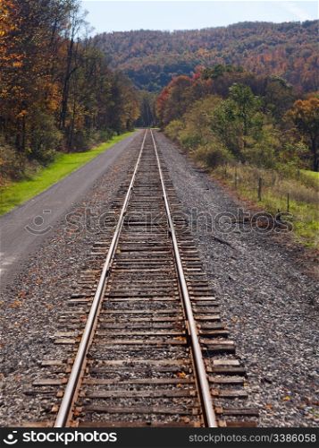 Cycling and hiking path besides railway lines in rural mountains in autumn
