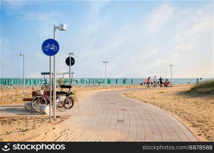 Cycling path with signal near beach on blue sky.