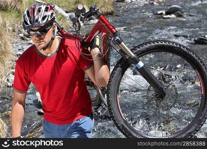 Cyclist carrying bike in river