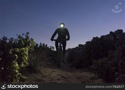 Cyclist descends the hill at night lit by lantern