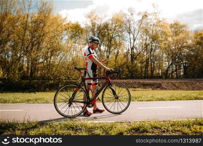 Cyclist in helmet and sportswear, cyclocross training on asphalt road. Male sportsman rides on bicycle. Workout on bike path