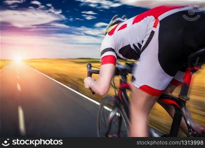 Cyclist in helmet and sportswear rides on bicycle, speed effect, back view. Workout on bike path, cycling. Cyclist rides on bicycle, speed effect
